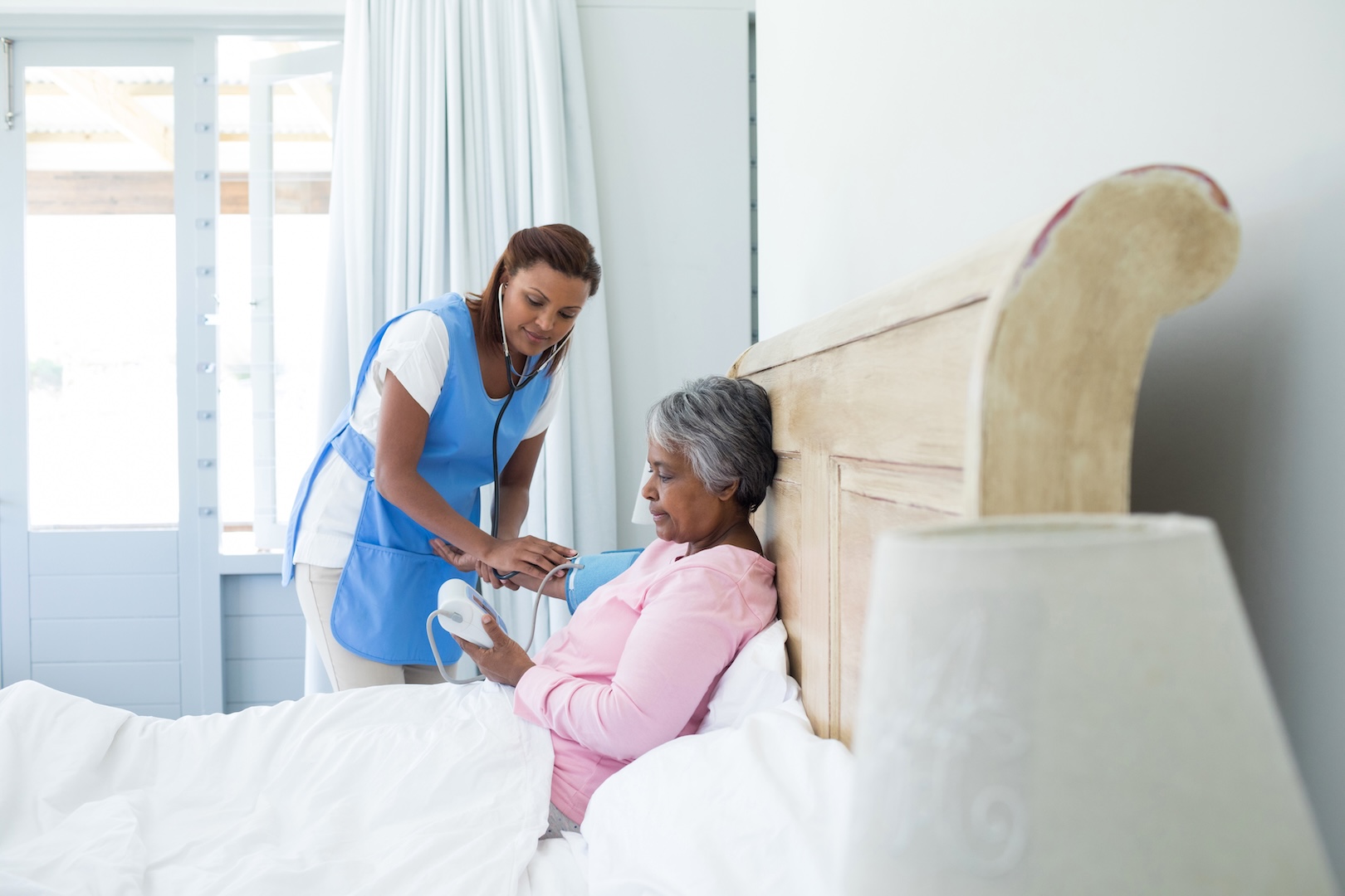 A nurse measures the blood pressure of a senior woman at home.